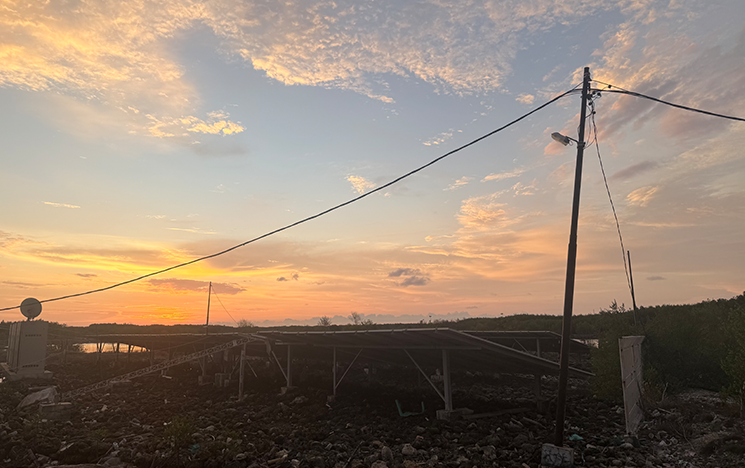 A sunset over a remote Indonesian village with electricity poles pictured