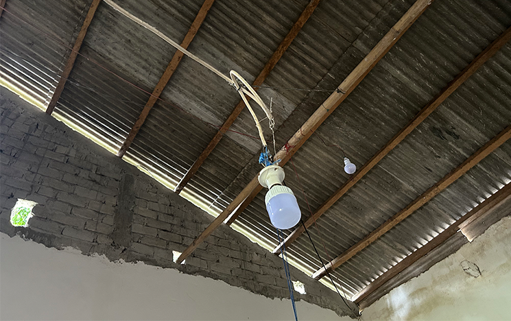Lightbulb hanging from a corrugated iron roof.