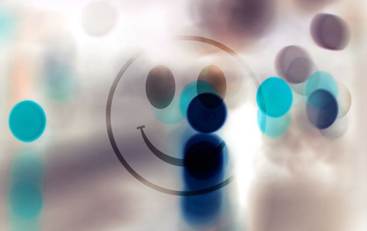 Smiley face line drawing behind a haze covered with blue coloured dots