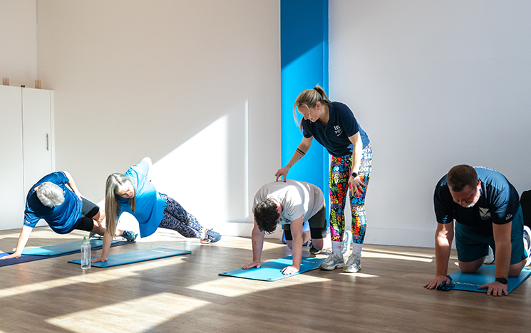 Staff stretching on mats in Active Arches, assisted by an instructor