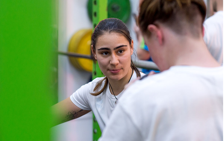 A student talking to another student whose back's to the camera.