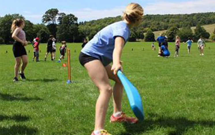 A young girl playing cricket
