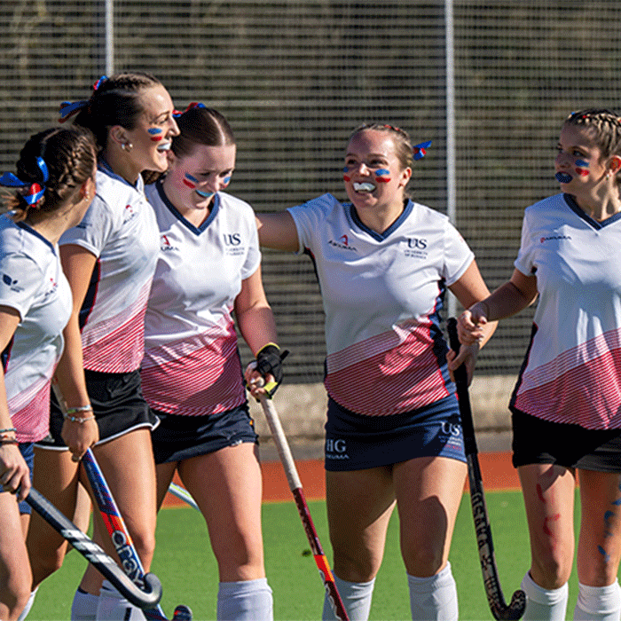 Women's hockey team celebrating on the pitch