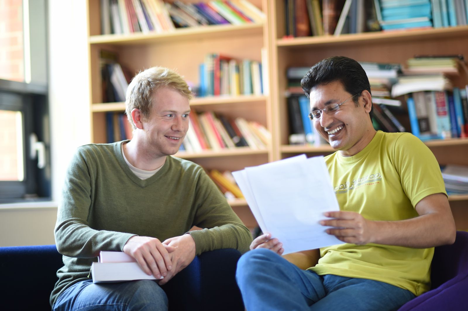 Two PhD students sitting together smiling as they discuss their work at the University of Sussex