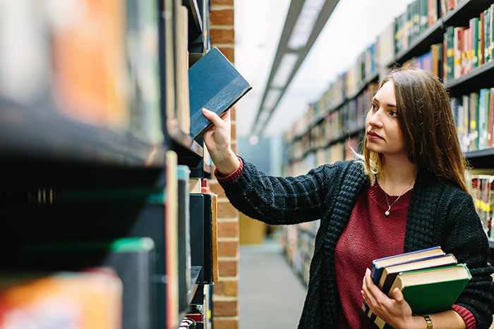 A PhD student uses the library to find books for her project at the University of Sussex