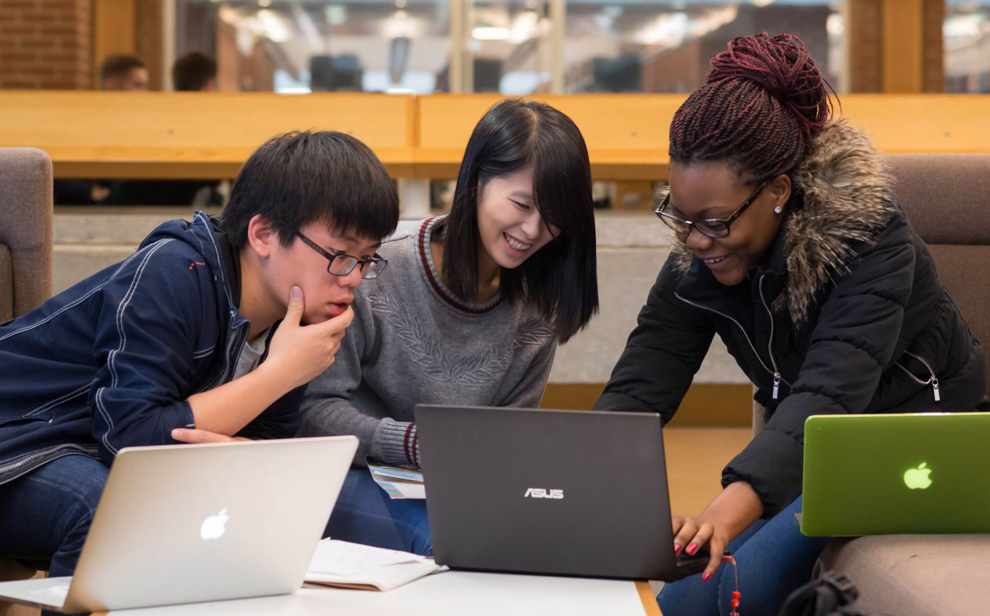 Three PhD students work together on their laptops for a project at the University of Sussex