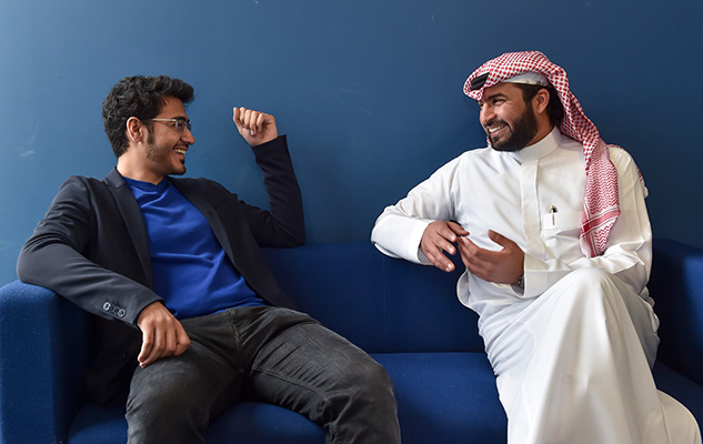 Two male international students at Sussex University, sitting on a sofa and talking to each other