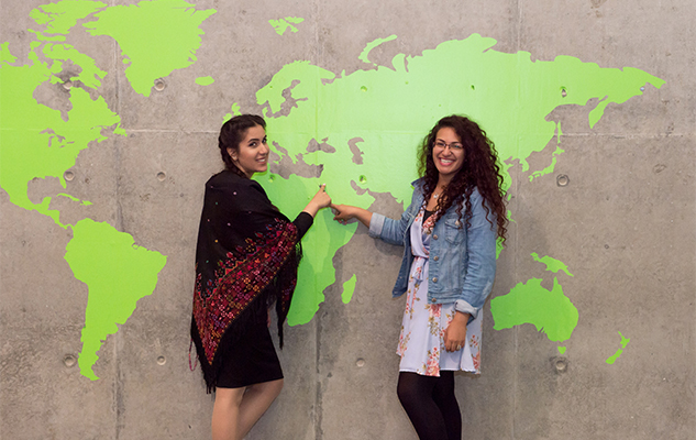 Two international students who study at Sussex University in the UK, pointing to a giant map
