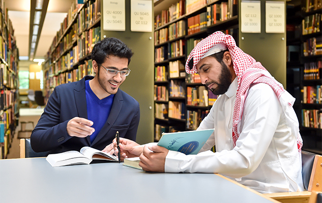Two male Middle Eastern students studying in the University of Sussex library
