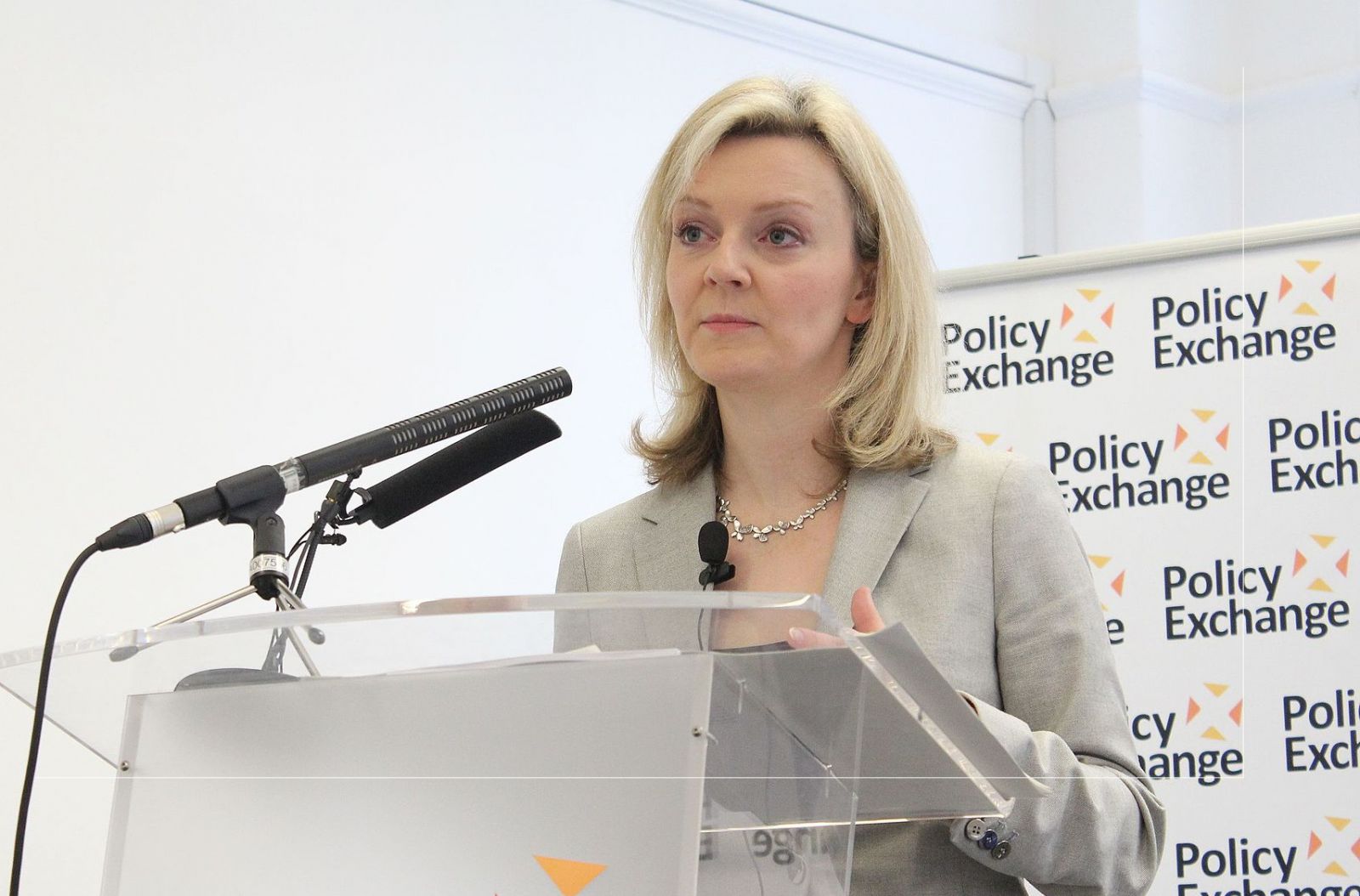 A photo of Liz Truss, current Home Secretary, standing at a podium