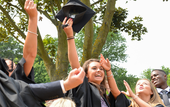 New graduates toss their hats, known as mortar boards, into the air