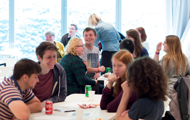 Students at a social event. The students are sat around tables