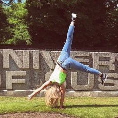 Lauren - Sussex student doing a cartwheel in front of the Sussex sign