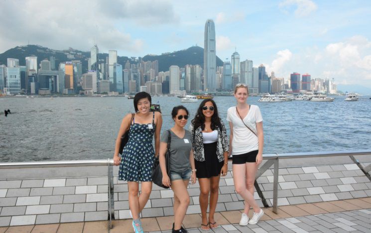 Icon: Exchange students posing in front of a city skyline in Asia