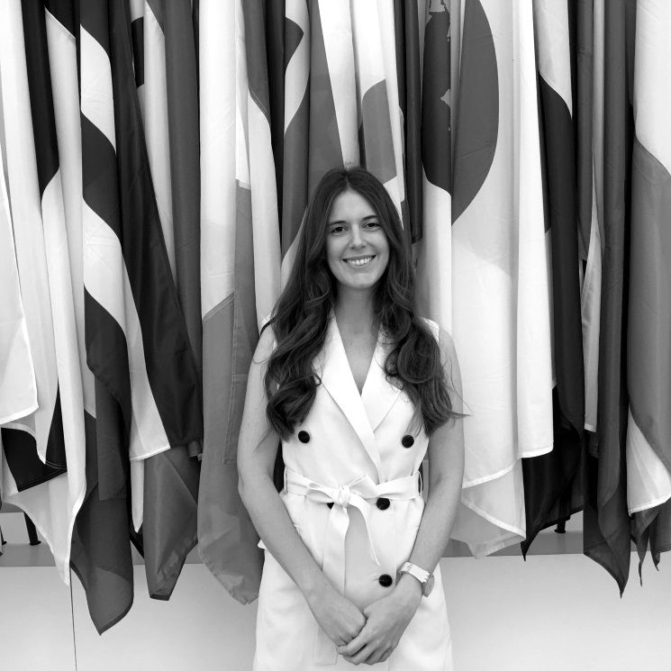 Sofia, an MA student in Corruption, standing in front of some flags