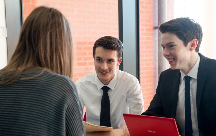 ICON: two students in business clothing speaking about their business project in a meeting