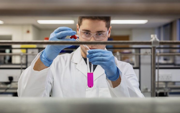 ICON: a science student in a lab mixing chemicals in a flask