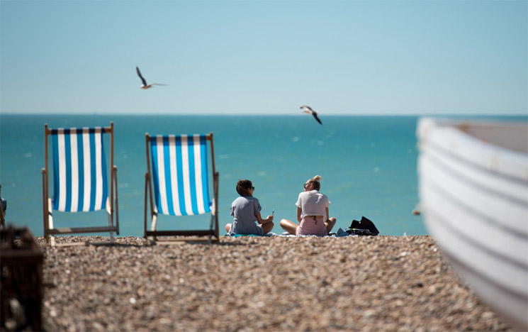People sit on Brighton Beach