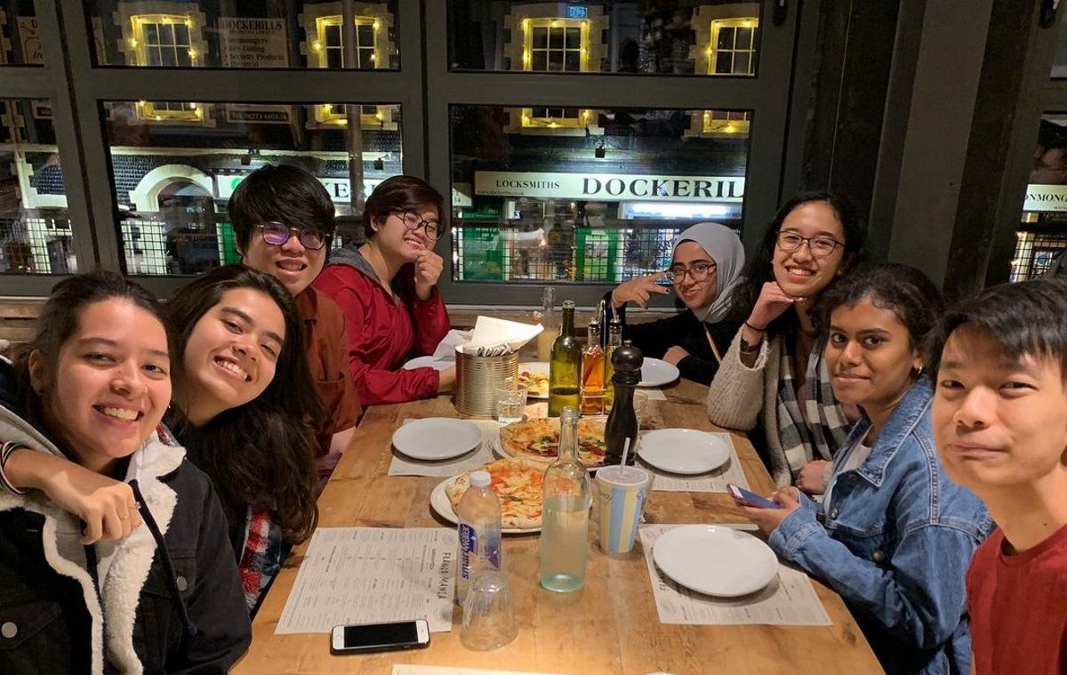 Eight students sitting in a restaurant face the camera
