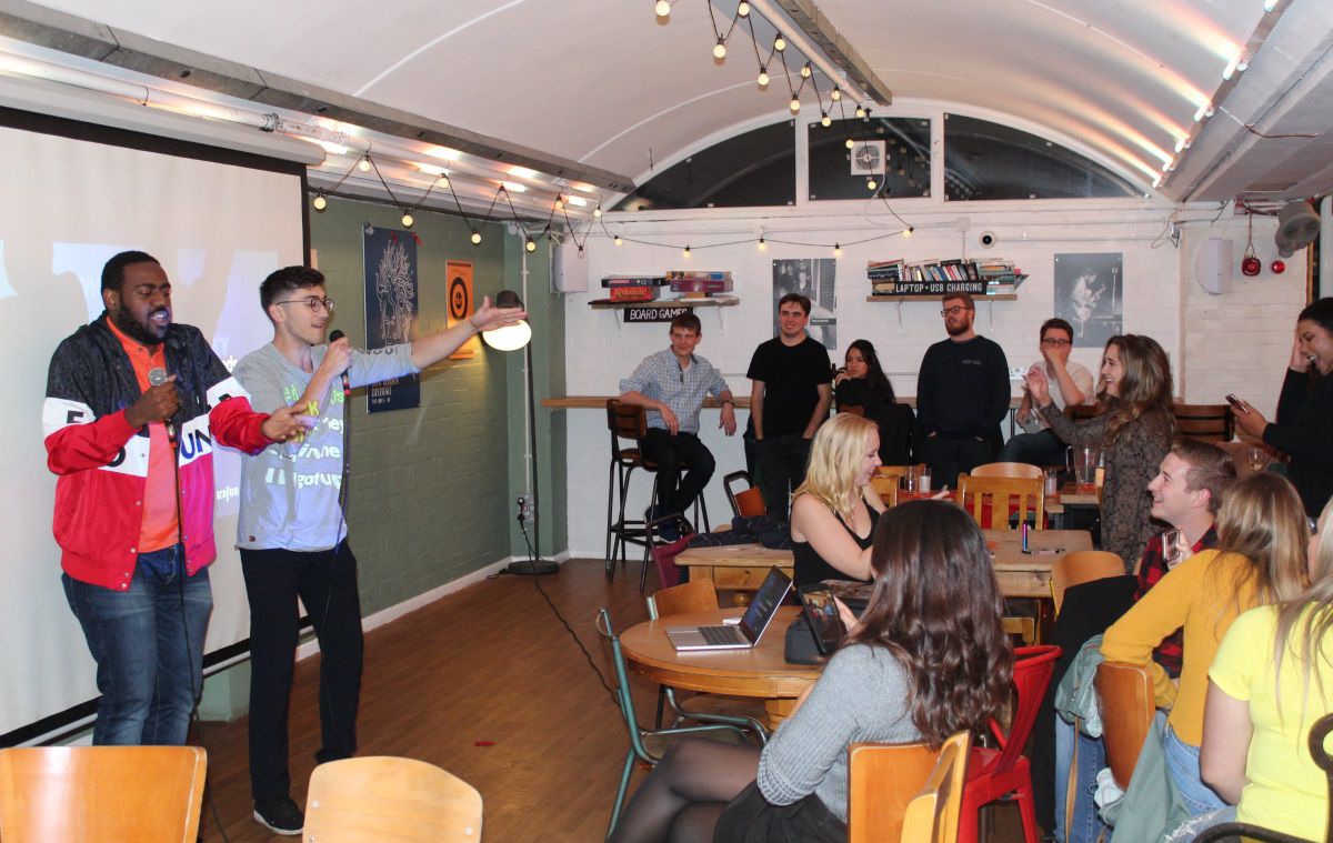 Two students sing to a crowd in a student bar