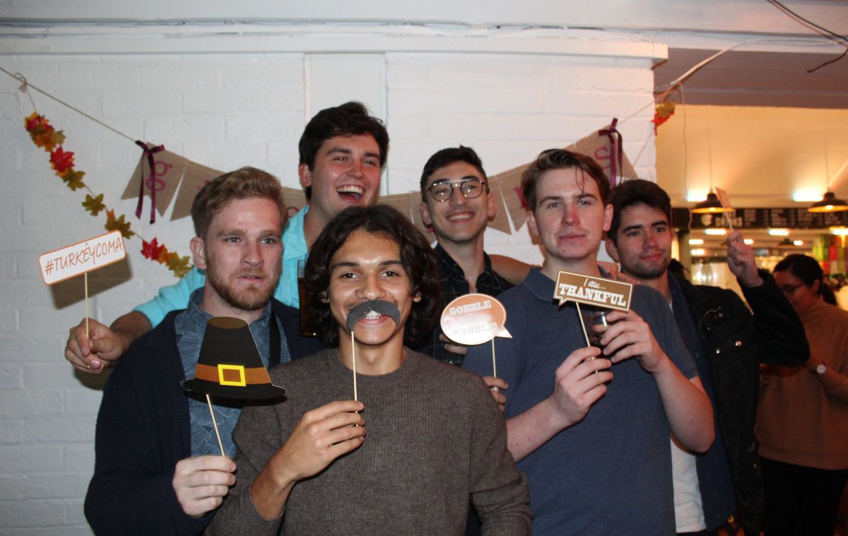 a big group of students smile to the camera holding lots of props