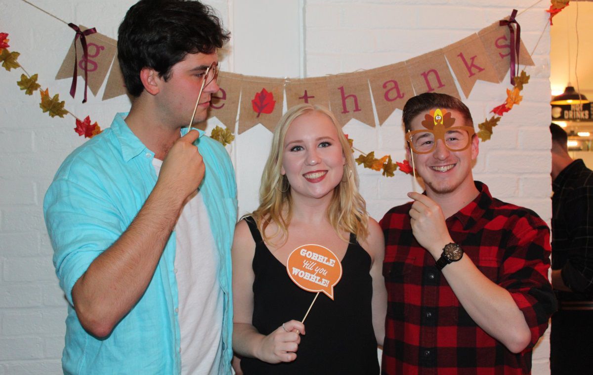 three students pose for a photo holding props, including fake glasses