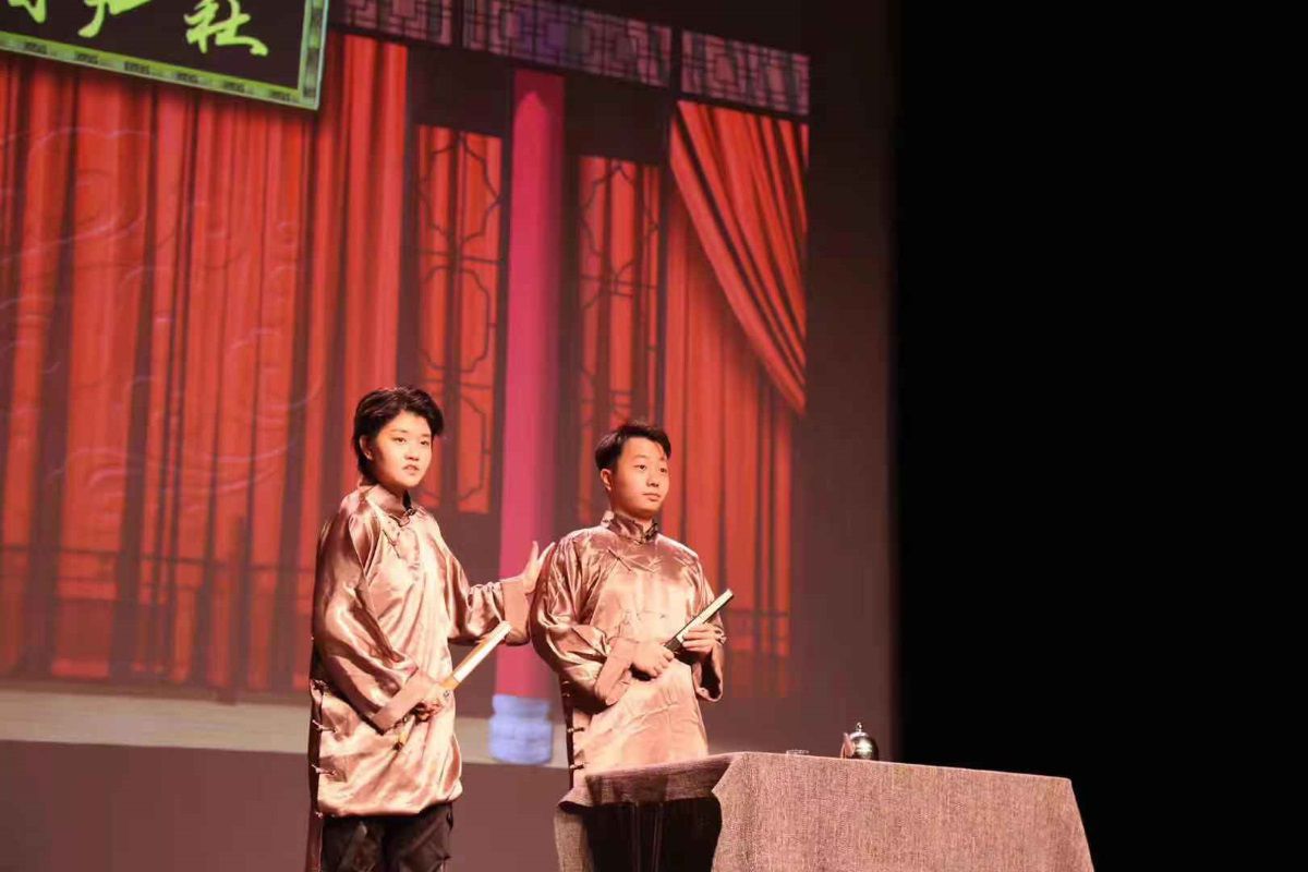 Two students dressed in traditional Chinese clothing on a stage