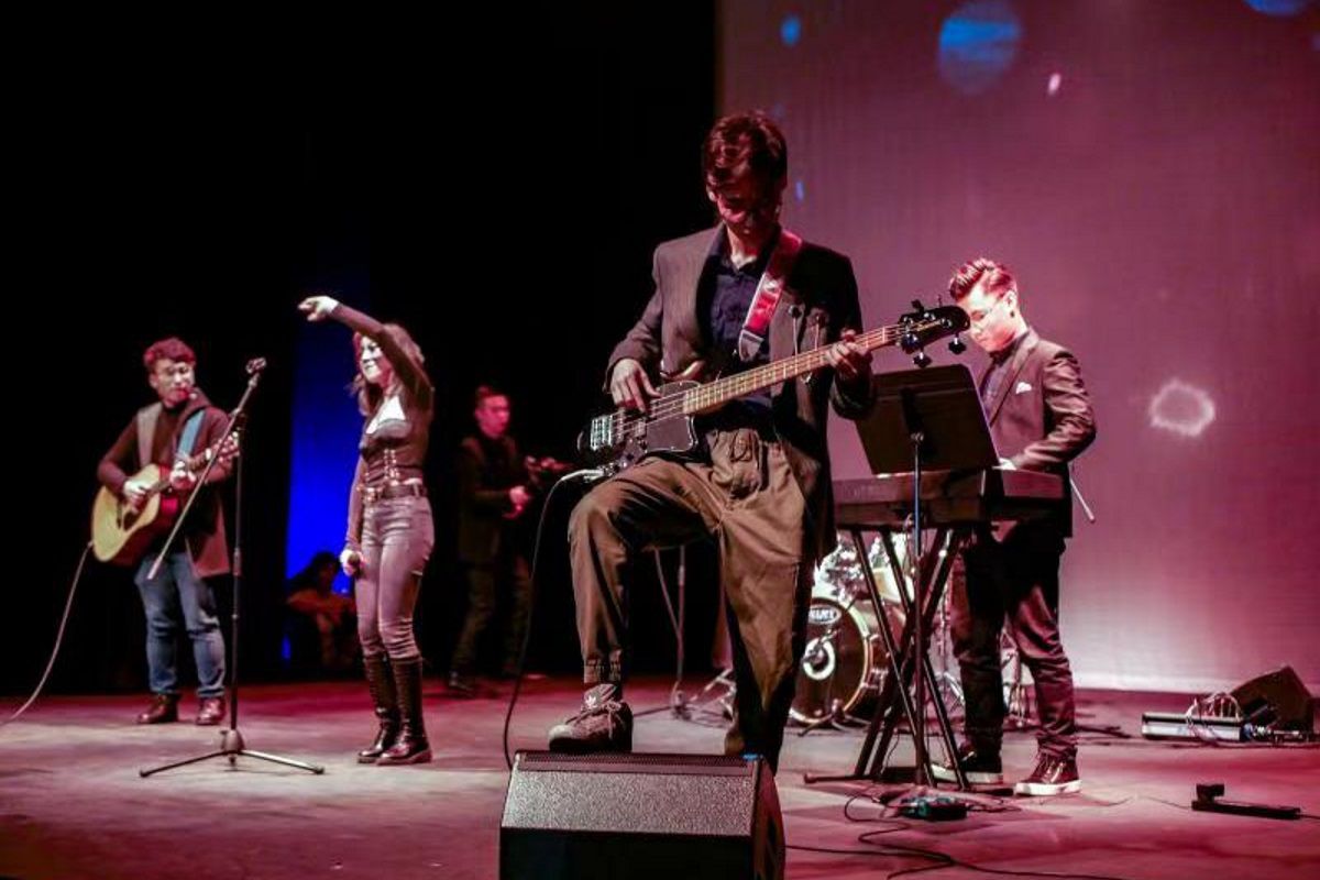 A rock band play music in front of an audience