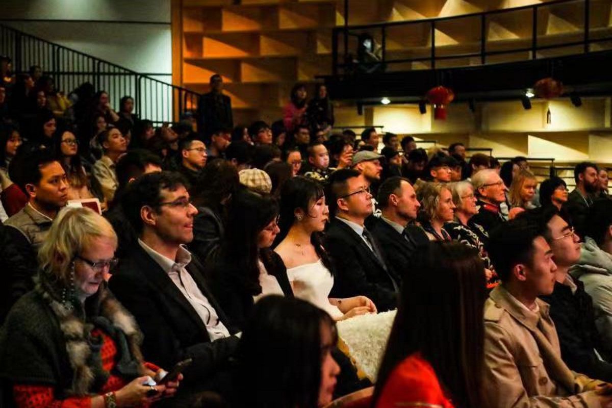An audience in a dark theatre watch a performance