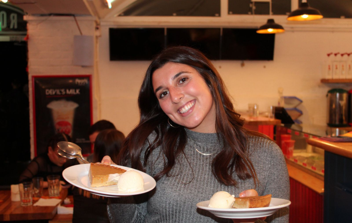 Canadian student holds up two places of dessert to camera, smiling