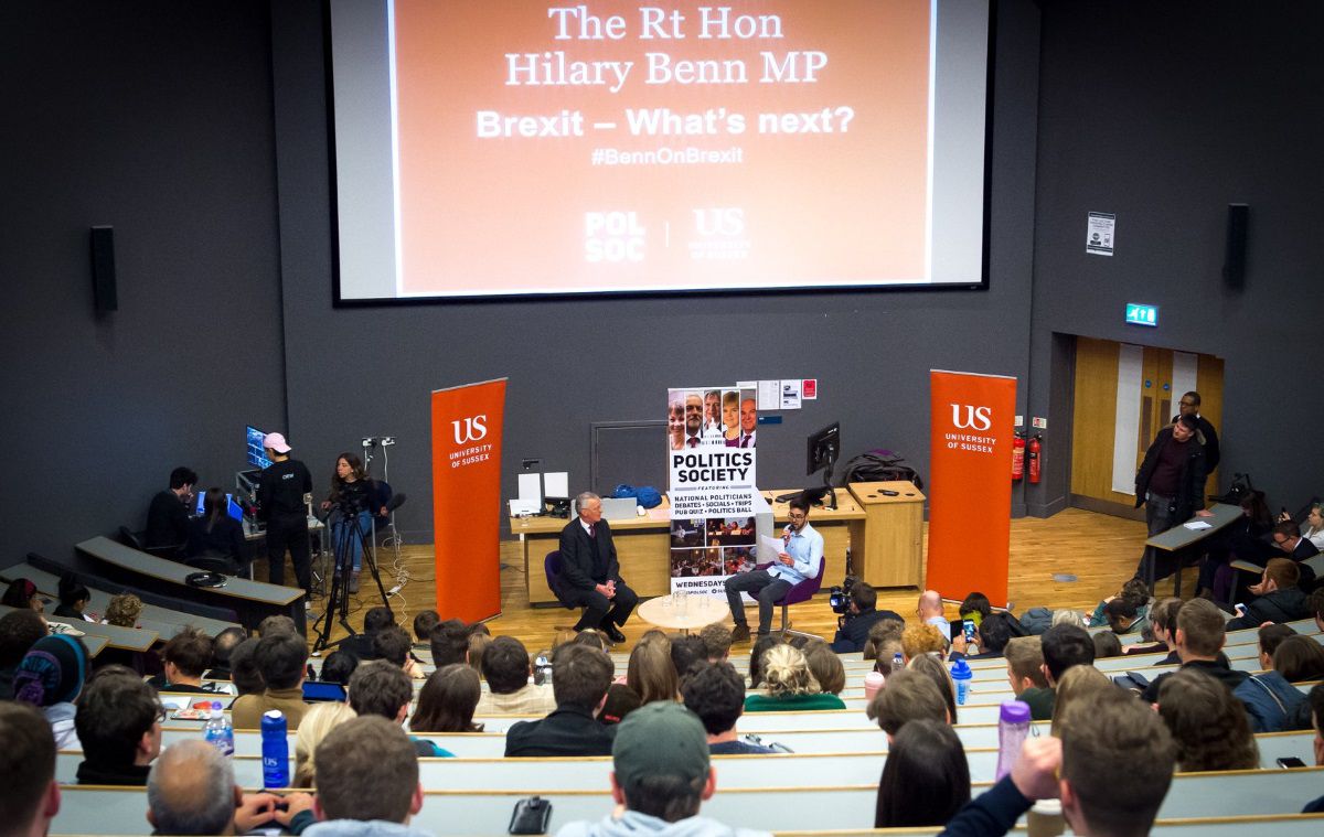 A crowded theatre watches an interview between a student and a political figure