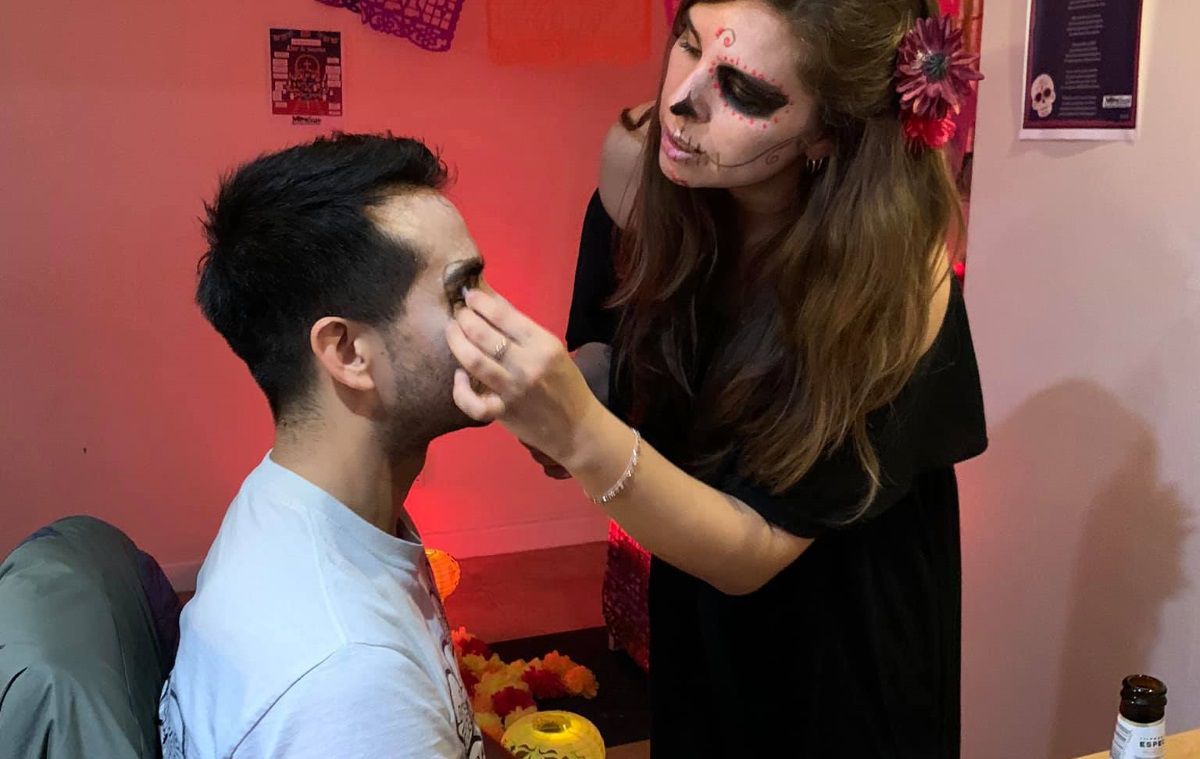 A student paints Day of the Dead facepaint on another student