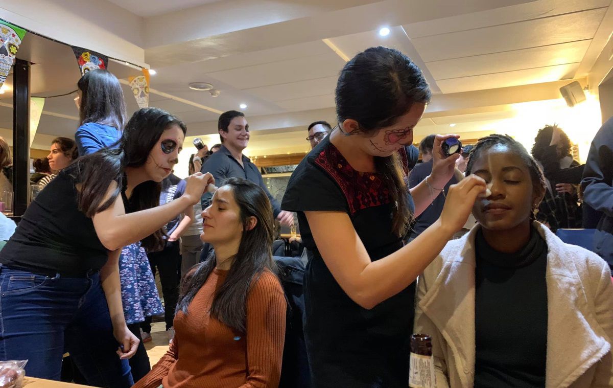 Two students paint two other students with facepaint to celebrate Mexican Day of the Dead