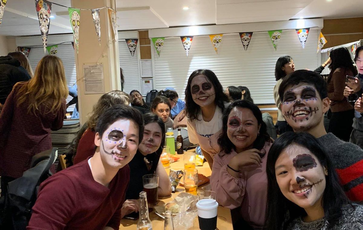 Several students in Day of the Dead outfits and decorations pose for the camera
