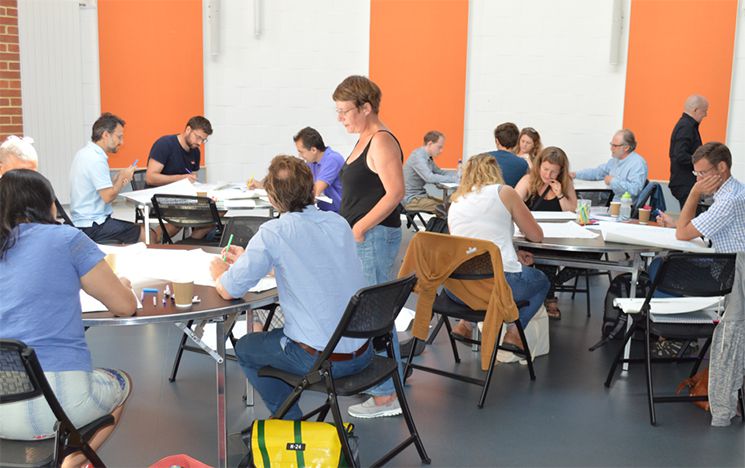 A workshop taking place, with pen and paper activities on a number of tables