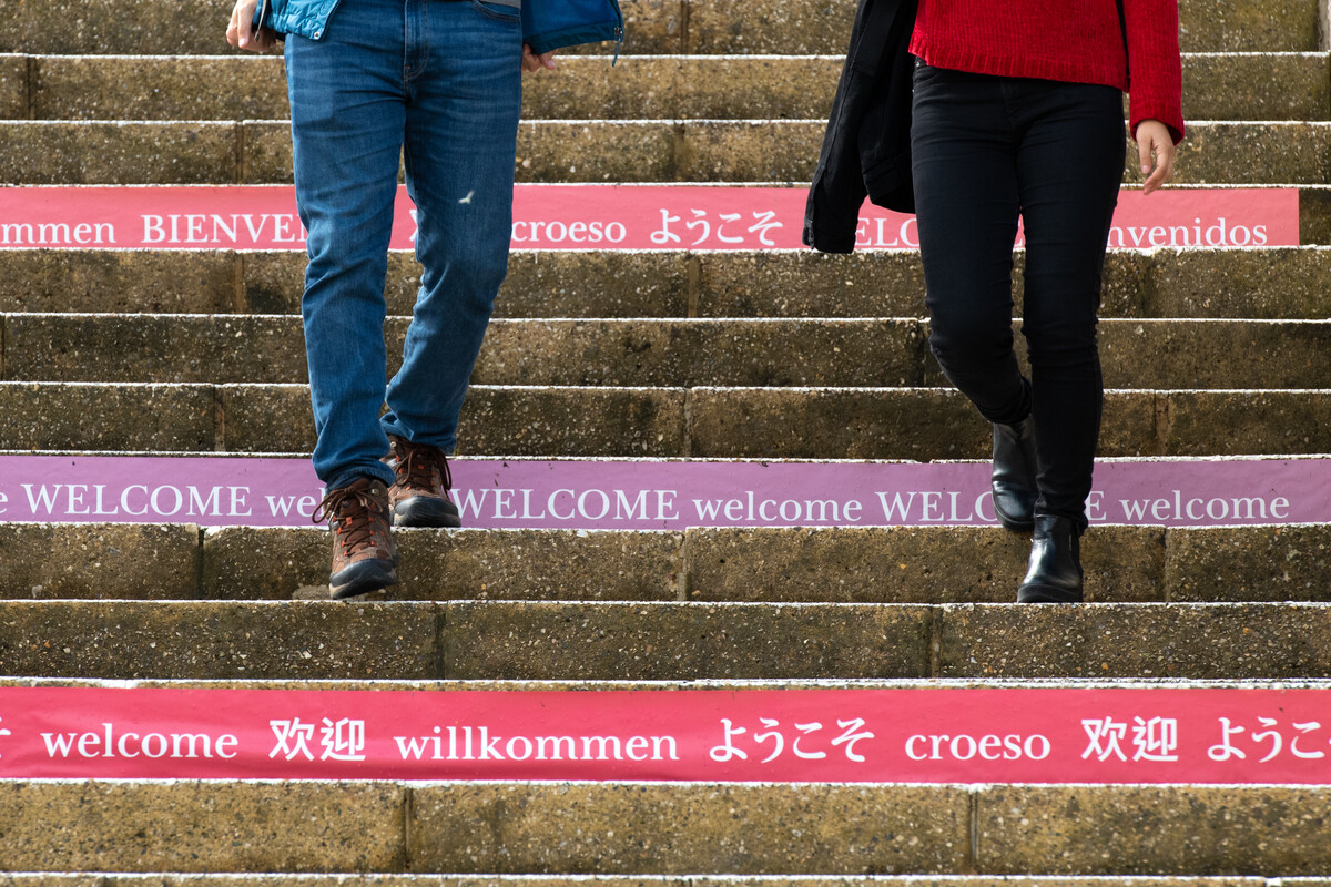 A view of two people walking down steps adorned with the word 'welcome' in different languages