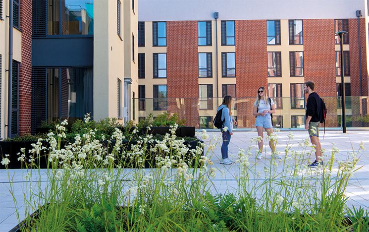 Three students standing outside campus accommodation