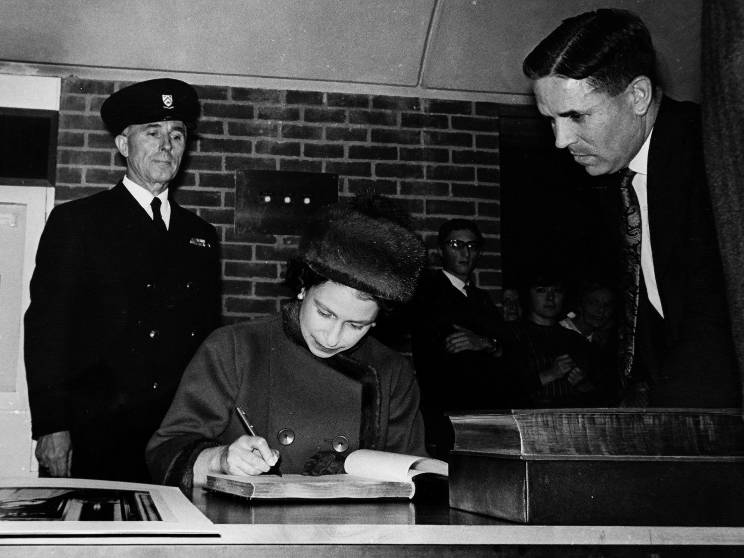 Her Majesty signs the visitors' book