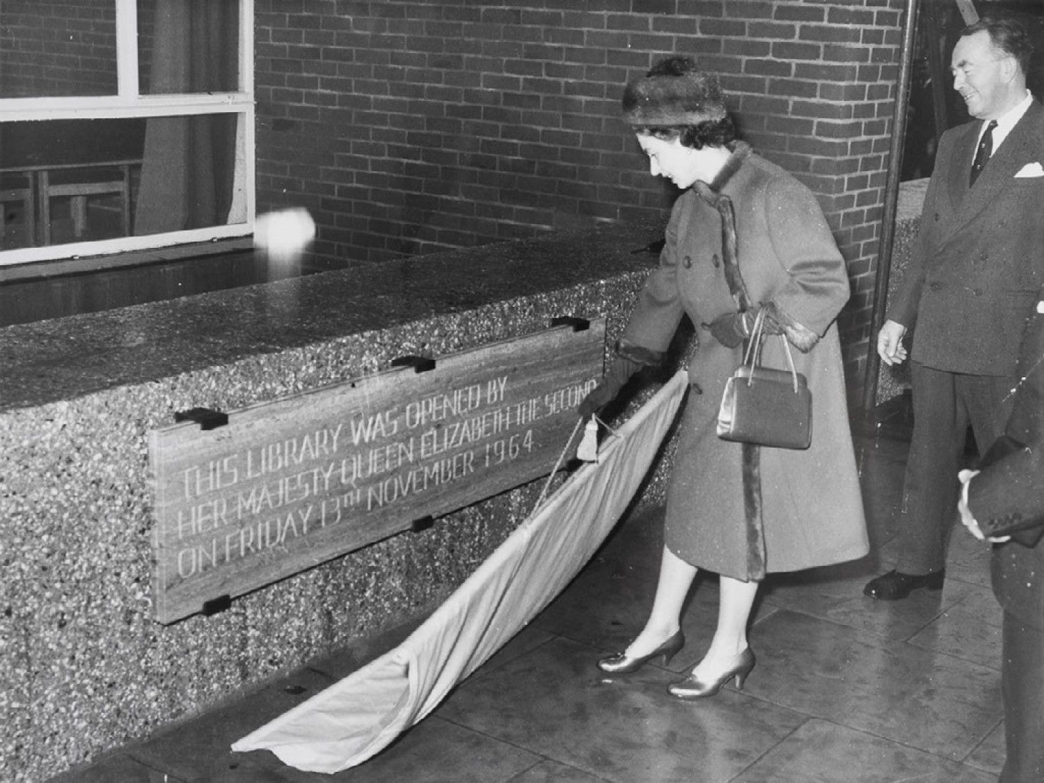 The Queen officially unveils a plaque that reads as follows: This Library was opened by Her Majesty Queen Elizabeth The Second on Friday 13th November 1964