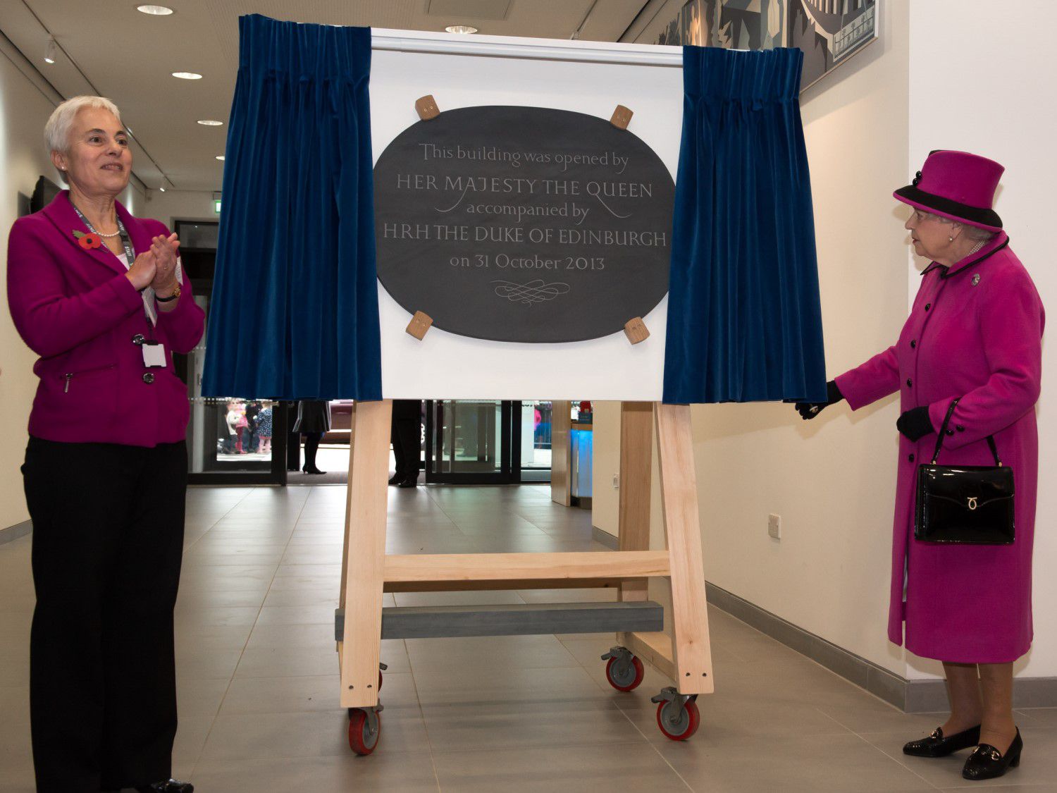 Her Majesty unveils a plaque marking the opening of The Keep, with a member of staff from the archive