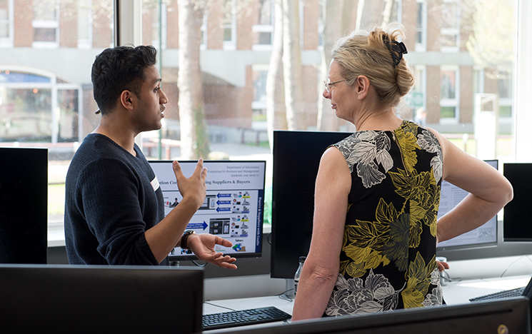 Two people discussing a project infront of a computer screen