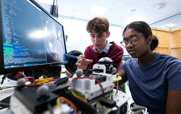 Two students work together in front of a computer in the electronics lab.