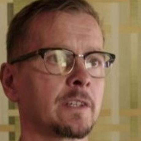 Image of Jon Mitchell with wayfarer glasses in front of geometric patterned background