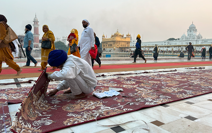 Man preparing carpet to fit in the Golden Temple in Amritsar
