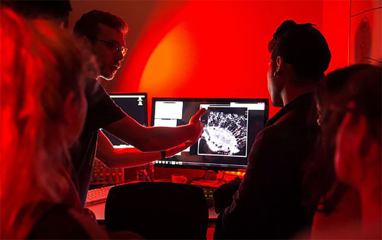 A group of people gathered around a computer, looking at an image of the brain on the screem