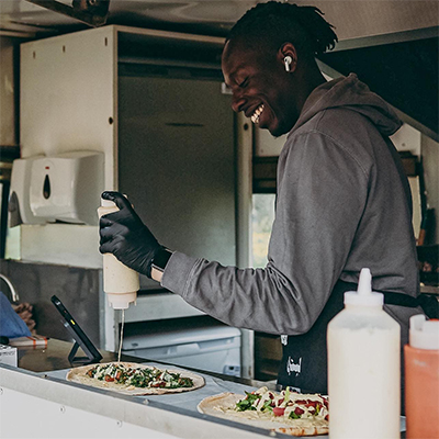 A person putting toppings on a pizza