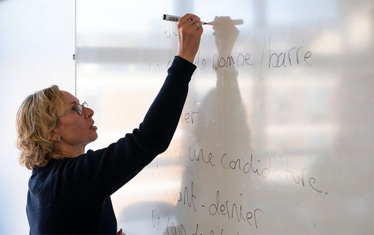 Teacher writing in French on a whiteboard