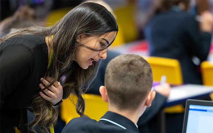 
A female teacher trainee helping a young student in class