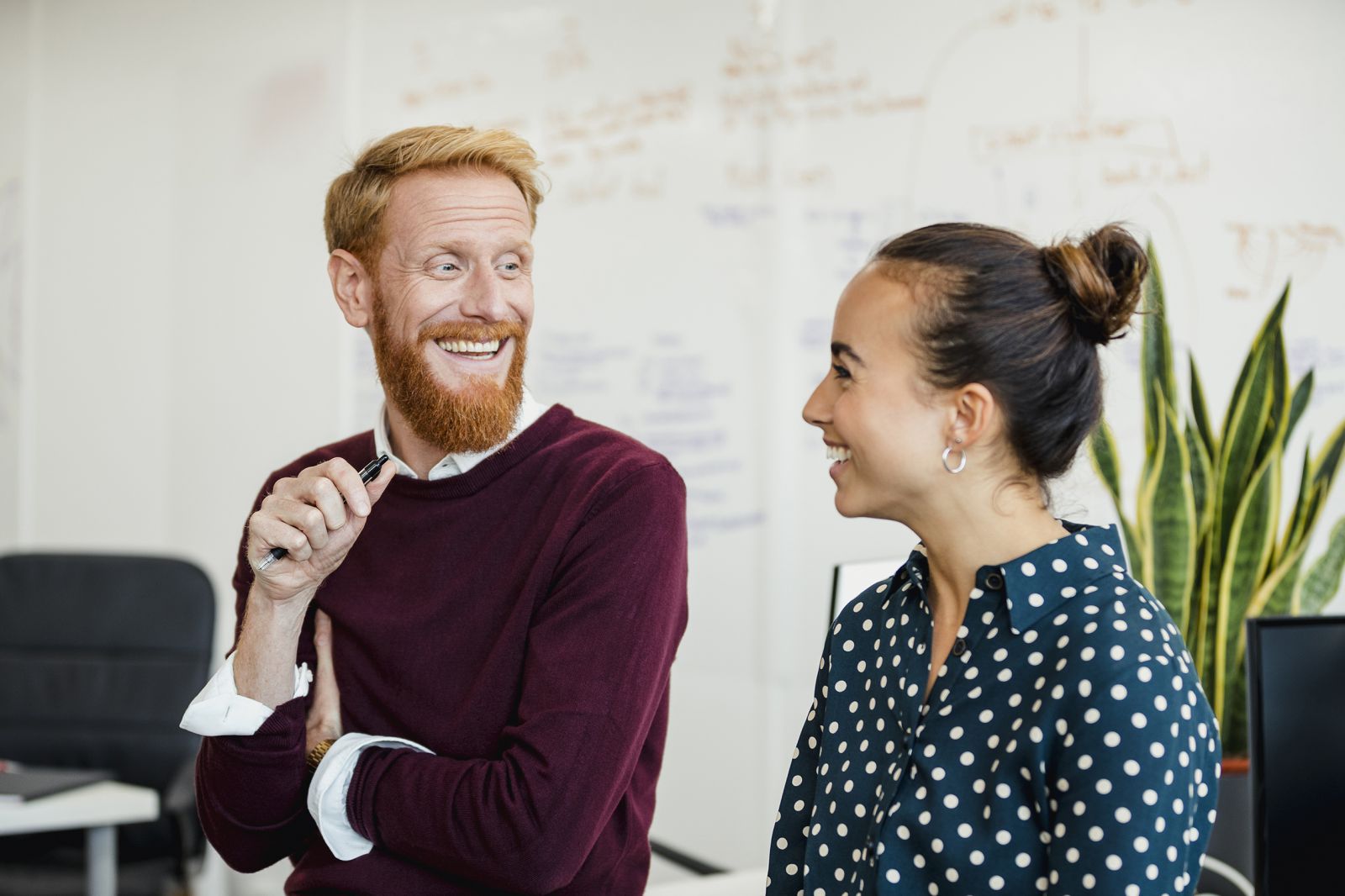 Two people talking in front of a white board