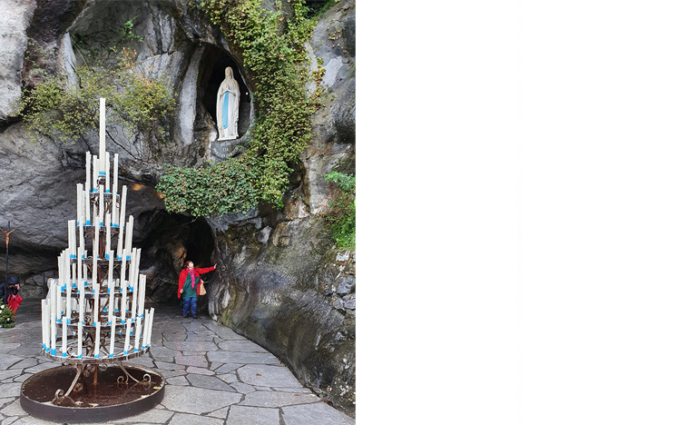 A pilgrim touches the rock in the grotto at Lourdes.